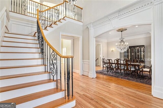 stairway featuring ornamental molding, a chandelier, and hardwood / wood-style floors