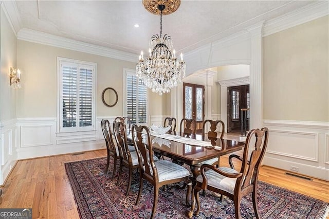 dining area with crown molding, a chandelier, light hardwood / wood-style floors, and french doors