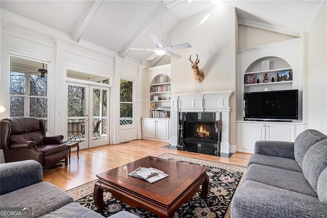 living room featuring vaulted ceiling with beams, built in features, a fireplace, and light hardwood / wood-style floors