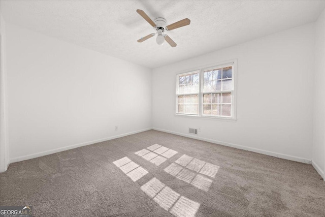 spare room featuring ceiling fan, light colored carpet, and a textured ceiling