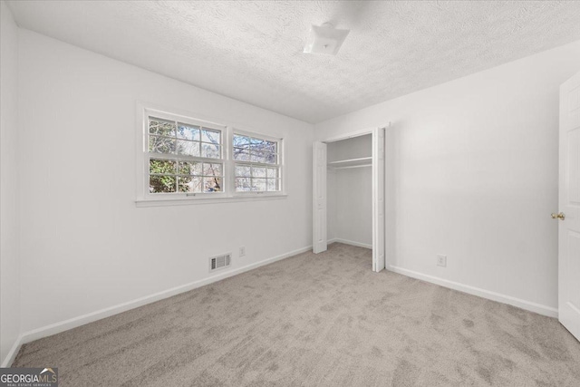 unfurnished bedroom featuring light carpet, a closet, and a textured ceiling