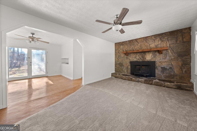 unfurnished living room featuring a textured ceiling, ceiling fan, light carpet, and a fireplace