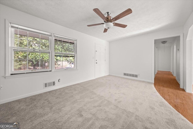 carpeted spare room with ceiling fan and a textured ceiling