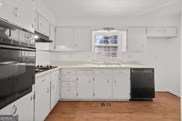 kitchen featuring sink, light hardwood / wood-style flooring, white cabinets, and black appliances