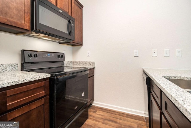 kitchen with baseboards, black appliances, and wood finished floors