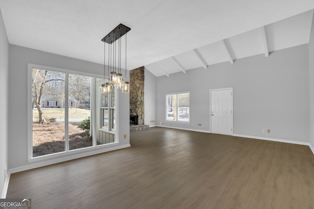 unfurnished living room featuring dark hardwood / wood-style floors, lofted ceiling with beams, a stone fireplace, and an inviting chandelier