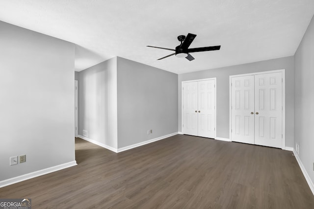 interior space featuring ceiling fan, two closets, and dark hardwood / wood-style floors