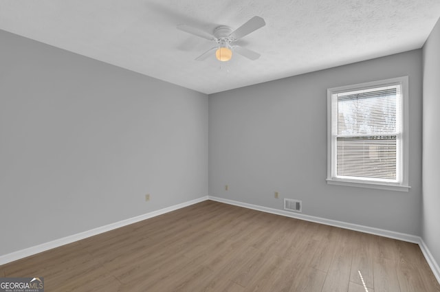 empty room featuring ceiling fan, a textured ceiling, and light wood-type flooring