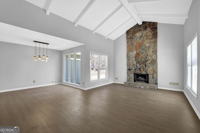 unfurnished living room with a fireplace, beamed ceiling, dark hardwood / wood-style flooring, and plenty of natural light