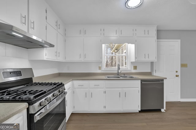 kitchen with dark wood-type flooring, stainless steel appliances, white cabinetry, and sink