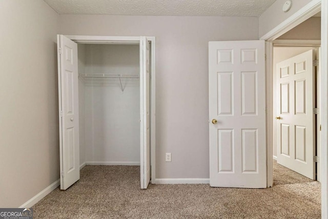 unfurnished bedroom with a textured ceiling, a closet, and carpet