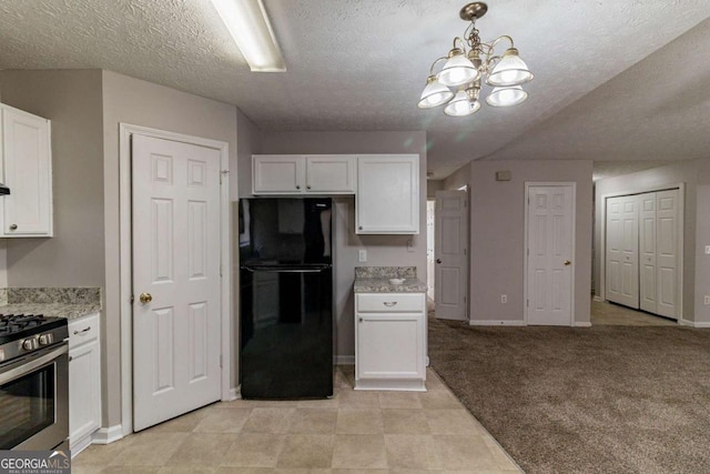 kitchen with white cabinets, stainless steel range with gas cooktop, a chandelier, and black fridge