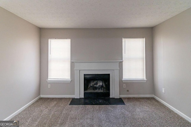 unfurnished living room with plenty of natural light, a textured ceiling, and dark colored carpet