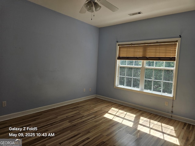 spare room with wood finished floors, a ceiling fan, and baseboards
