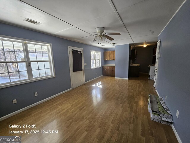 unfurnished living room with a ceiling fan, dark wood-style floors, and baseboards