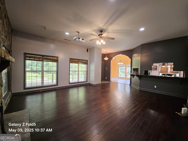 unfurnished living room with arched walkways, hardwood / wood-style floors, ceiling fan, recessed lighting, and a stone fireplace