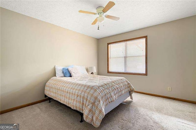 bedroom with ceiling fan, carpet floors, and a textured ceiling