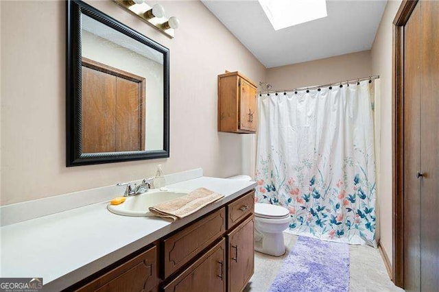 bathroom with toilet, vanity, a skylight, and a shower with curtain