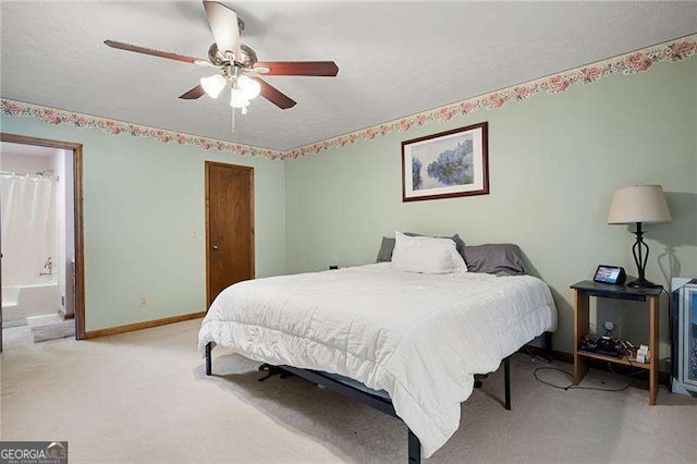 bedroom with ceiling fan, light colored carpet, and connected bathroom