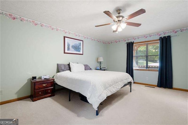 bedroom featuring ceiling fan, light carpet, and a textured ceiling