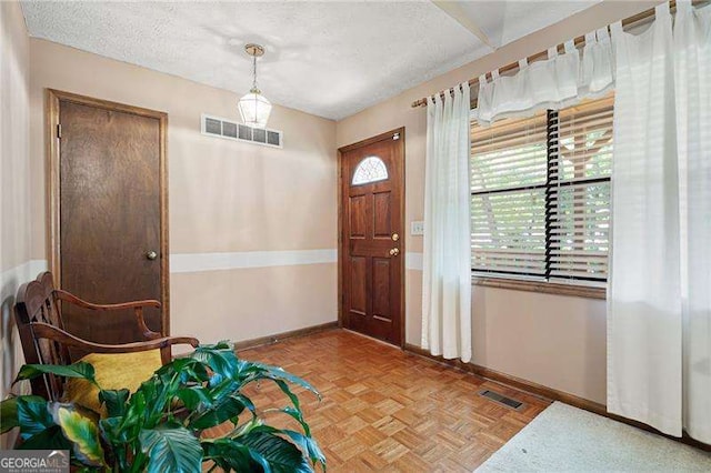 entryway featuring a textured ceiling and parquet flooring