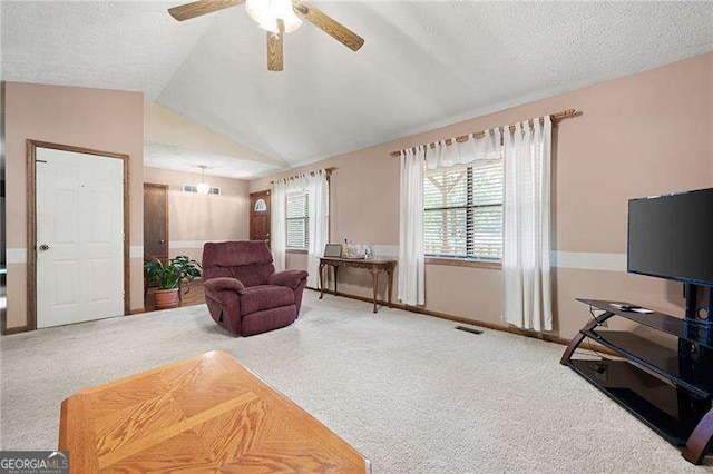 carpeted living room featuring ceiling fan, vaulted ceiling, and a textured ceiling