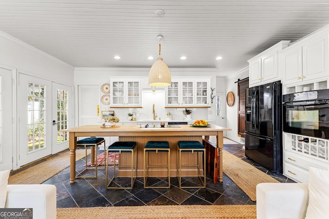 kitchen with a kitchen bar, hanging light fixtures, crown molding, white cabinets, and black appliances