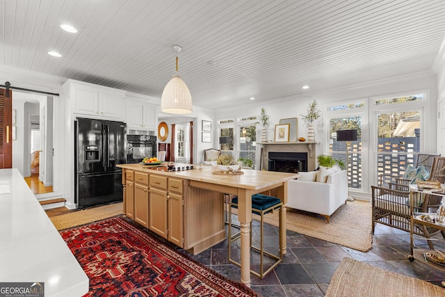 kitchen with pendant lighting, black appliances, a center island, wood ceiling, and a barn door