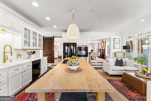 kitchen featuring black appliances, a barn door, sink, and white cabinetry