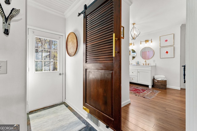 doorway to outside with crown molding, a barn door, and light hardwood / wood-style floors