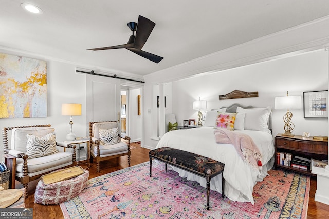 bedroom featuring ceiling fan, a barn door, crown molding, and hardwood / wood-style flooring