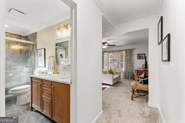 bathroom with a shower with shower door, vanity, toilet, ornamental molding, and ceiling fan