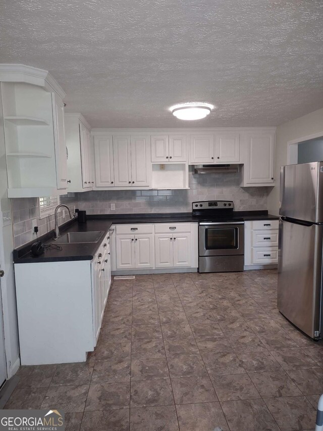 kitchen with tasteful backsplash, white cabinets, appliances with stainless steel finishes, and sink