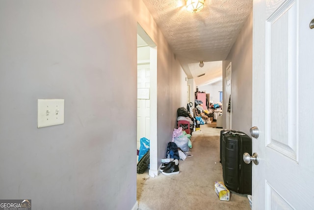 hall featuring light colored carpet, vaulted ceiling, and a textured ceiling