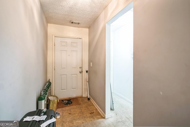 doorway with light colored carpet and a textured ceiling