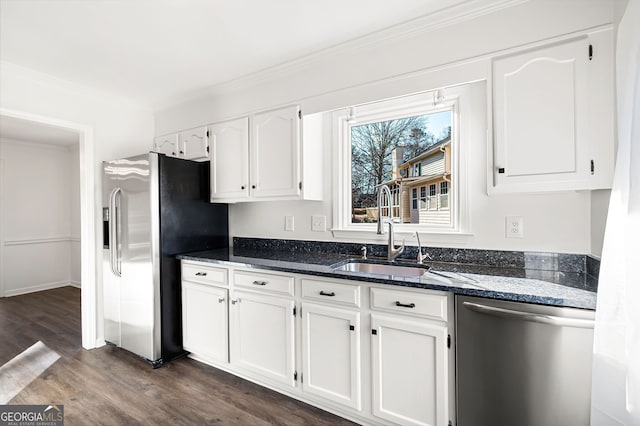 kitchen featuring white cabinets, dark hardwood / wood-style flooring, stainless steel appliances, dark stone countertops, and sink