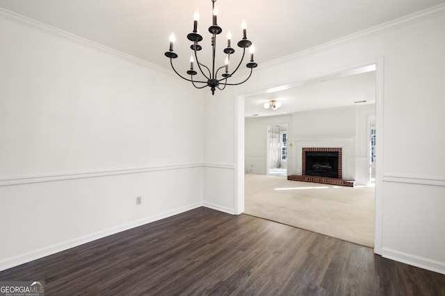 unfurnished living room featuring a brick fireplace, dark hardwood / wood-style floors, crown molding, and an inviting chandelier