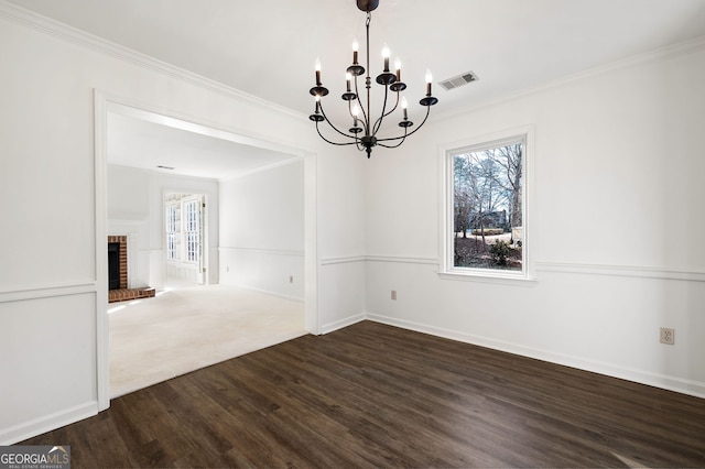 unfurnished dining area with a fireplace, dark hardwood / wood-style flooring, a notable chandelier, and ornamental molding