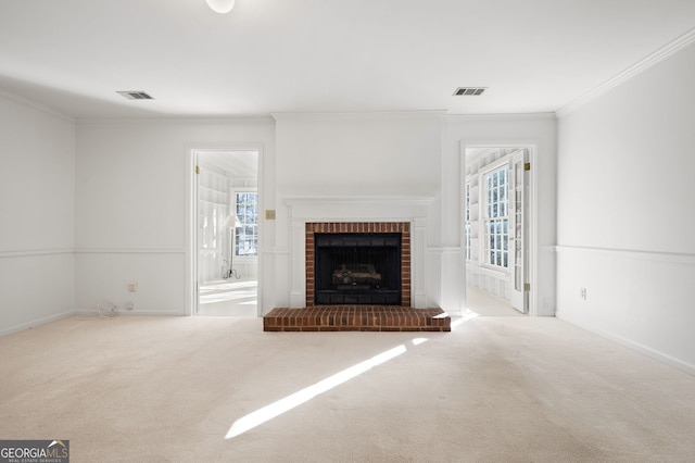 unfurnished living room with ornamental molding, a wealth of natural light, a brick fireplace, and light colored carpet