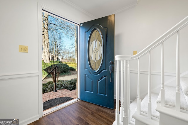 foyer entrance with dark hardwood / wood-style flooring, ornamental molding, and a healthy amount of sunlight