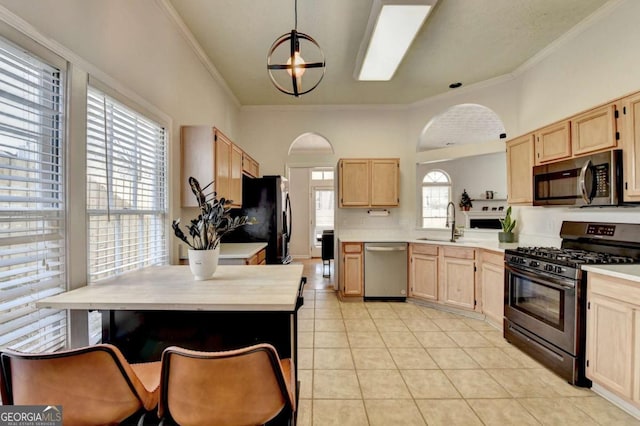 kitchen featuring decorative light fixtures, sink, stainless steel appliances, light tile patterned floors, and light brown cabinetry