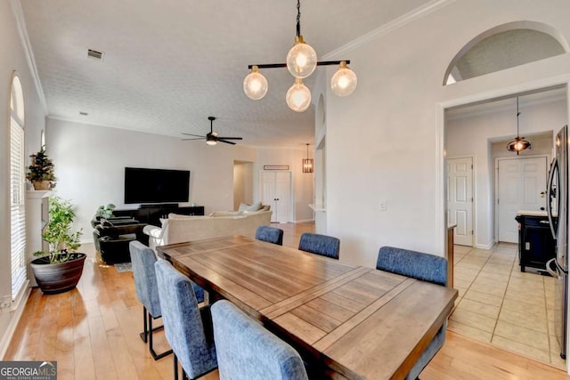 dining room with light wood-type flooring, ceiling fan, crown molding, and a textured ceiling