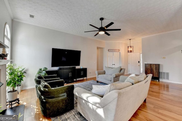 living room featuring a textured ceiling, crown molding, ceiling fan with notable chandelier, and light hardwood / wood-style flooring