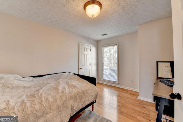 bedroom featuring a textured ceiling and light hardwood / wood-style flooring