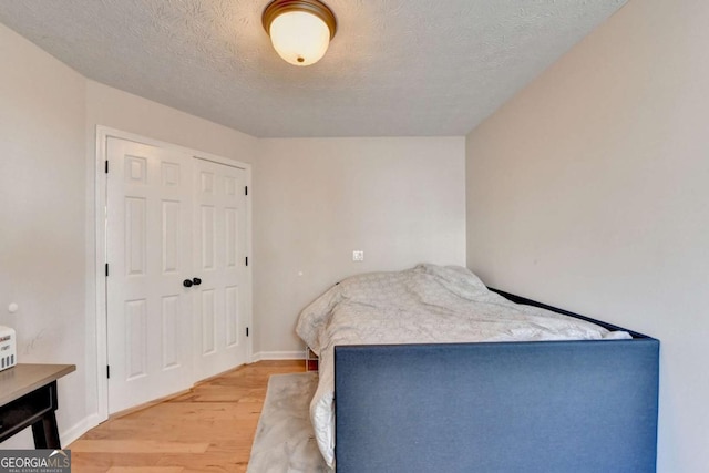 bedroom with a textured ceiling, a closet, and wood-type flooring