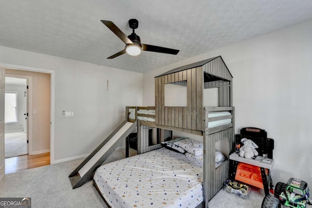 bedroom with light carpet, ceiling fan, and a textured ceiling