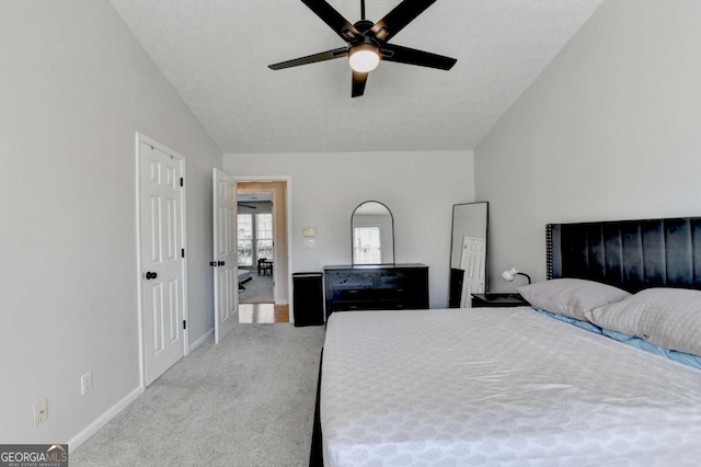 carpeted bedroom featuring ceiling fan, vaulted ceiling, and a textured ceiling