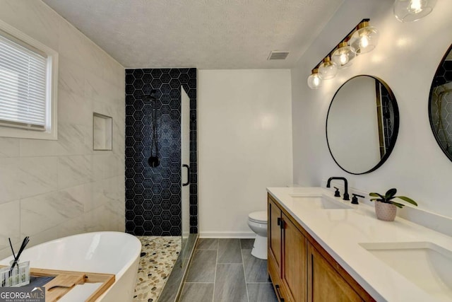 full bathroom featuring a textured ceiling, toilet, vanity, and separate shower and tub