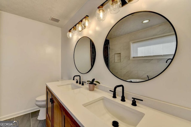 bathroom featuring a textured ceiling, toilet, and vanity