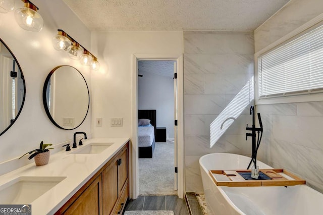 bathroom with vanity, tile walls, a textured ceiling, and a bath